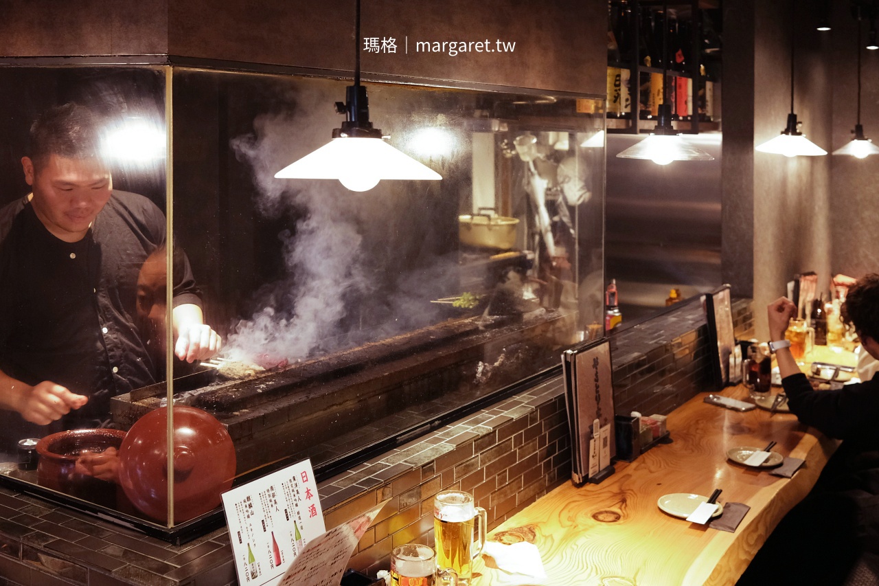 燒鳥炭壹2號店一樓吧檯全景，廚師在烤台後方專注工作，煙霧繚繞。