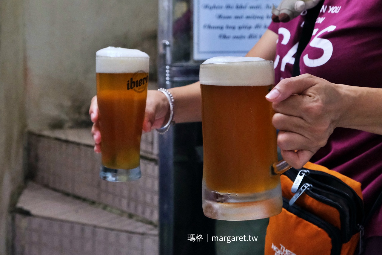 河內 Tuệ An 蒸米皮捲店的生啤酒，兩杯金黃色啤酒盛在透明啤酒杯中，表面覆著細緻綿密的白色泡沫