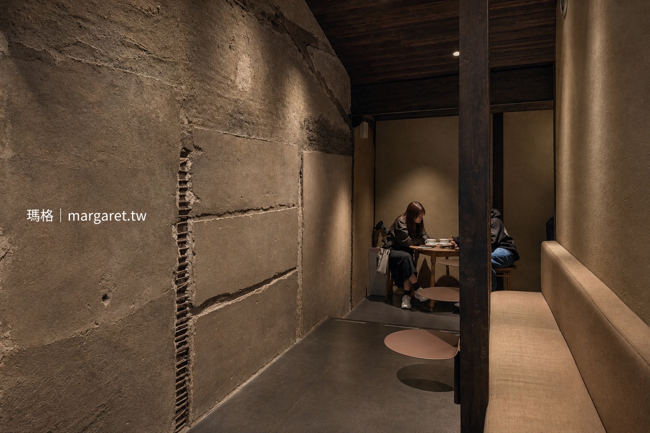 京都 Blue Bottle Coffee 六角店室內角落，保留斑駁粗糙土牆與深色木柱，沿牆設有長椅及小圓桌，營造安靜有隱私感的座位空間