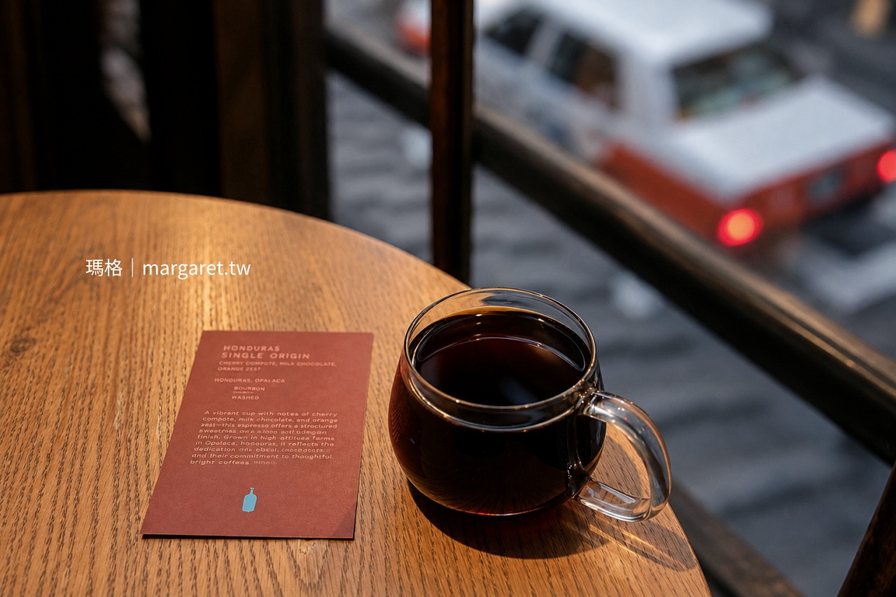 京都 Blue Bottle Coffee 六角店窗邊的宏都拉斯單品咖啡與風味介紹卡，窗外可見街道上的計程車