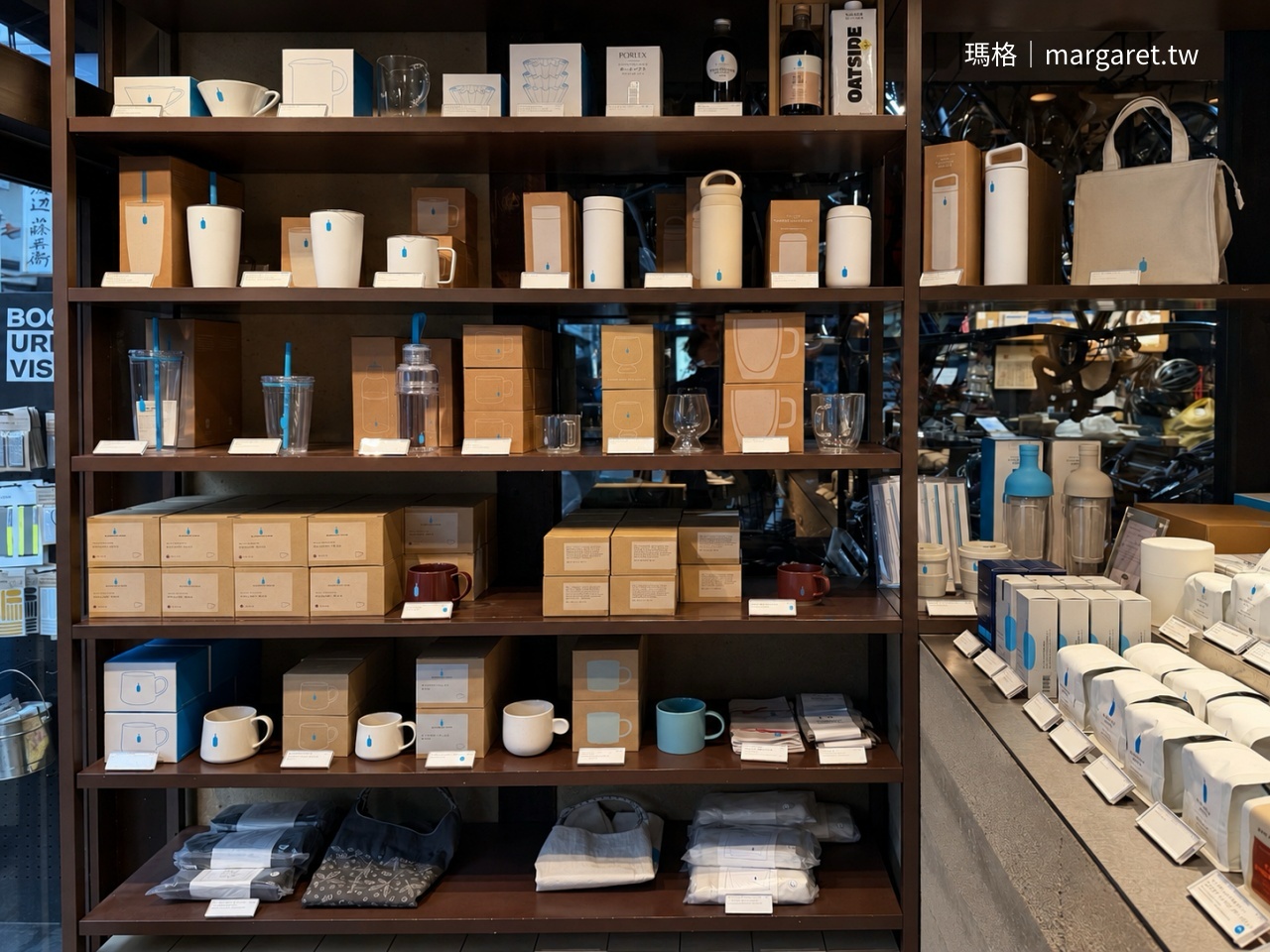 京都 Blue Bottle Coffee 六角店一樓木架上的周邊商品，包含陶瓷咖啡杯、隨行杯、保溫瓶、咖啡器具與布袋