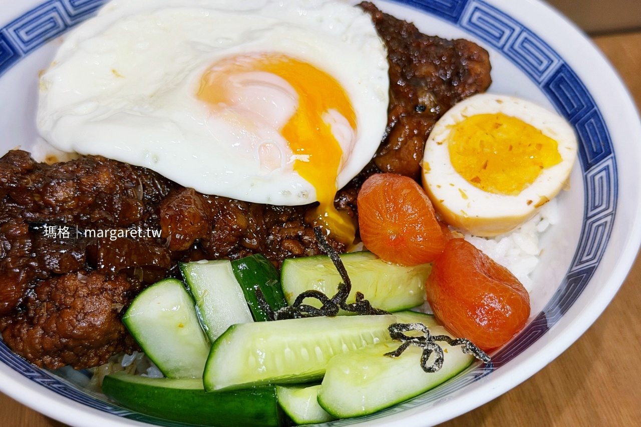 開囍滷肉專賣店滷大排飯加點荷包蛋，半熟蛋黃流淌在滷排骨與白飯上，旁邊搭配生切小黃瓜、醃番茄及半顆滷蛋