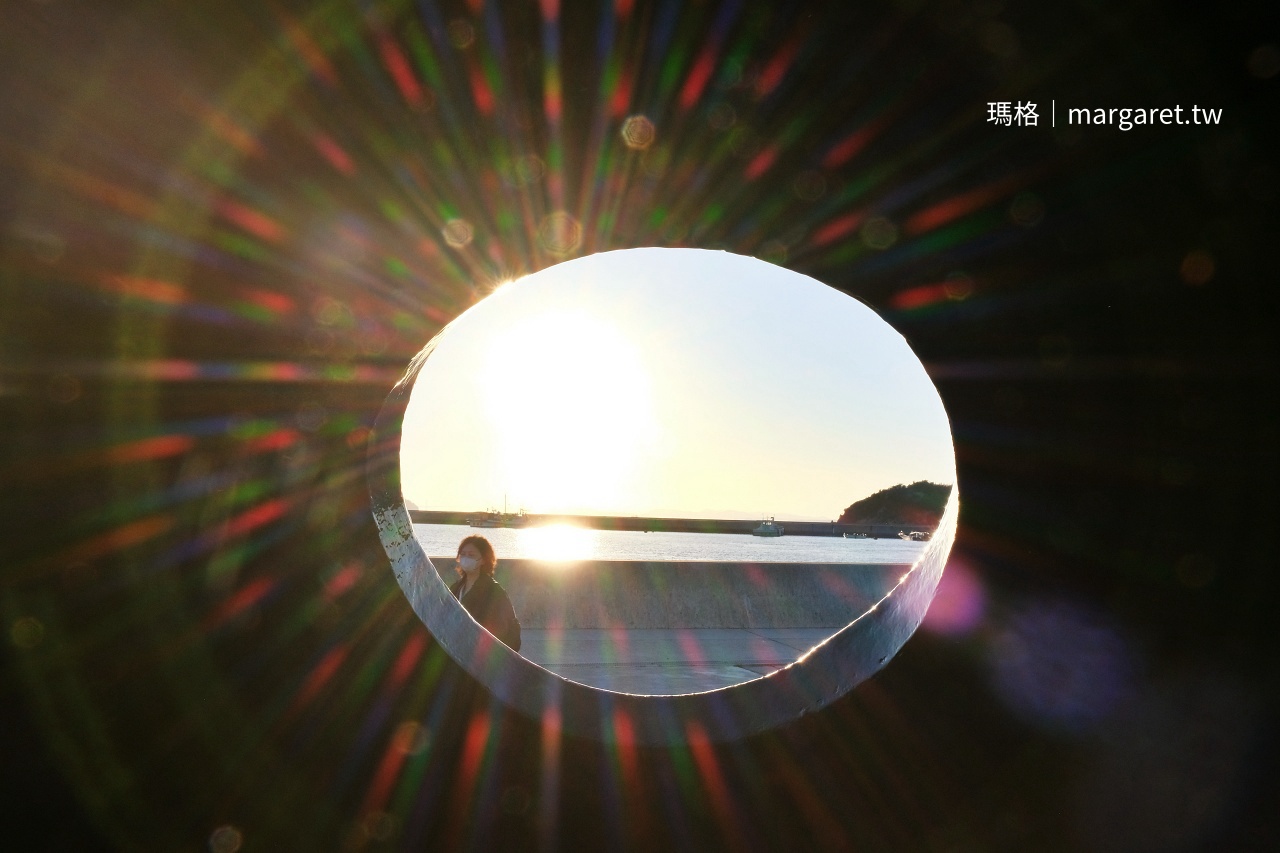 從直島紅南瓜內部圓洞遠眺宮浦港夕陽與人像光暈